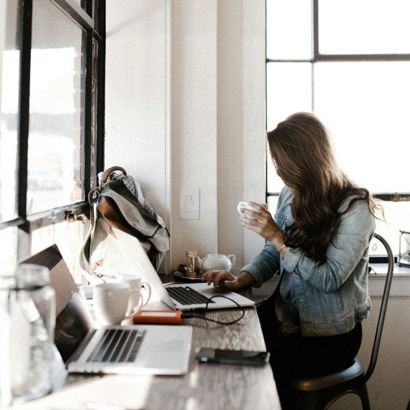 Woman browsing on a laptop with a cup of coffee.
