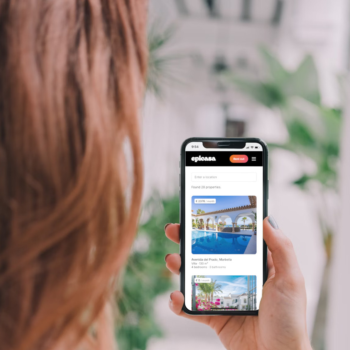 Woman holding a smartphone displaying the epicasa website.